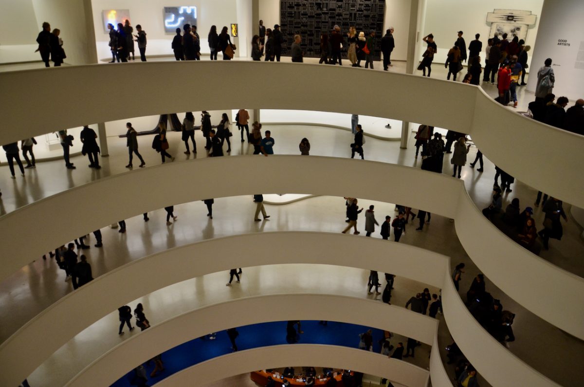 Several levels of the Guggenheim's ramped walk ways around the building all filled with people.