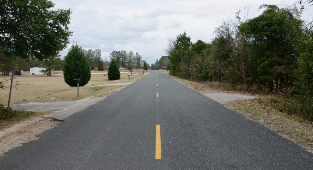 An empty rural road stretches out into the distance.