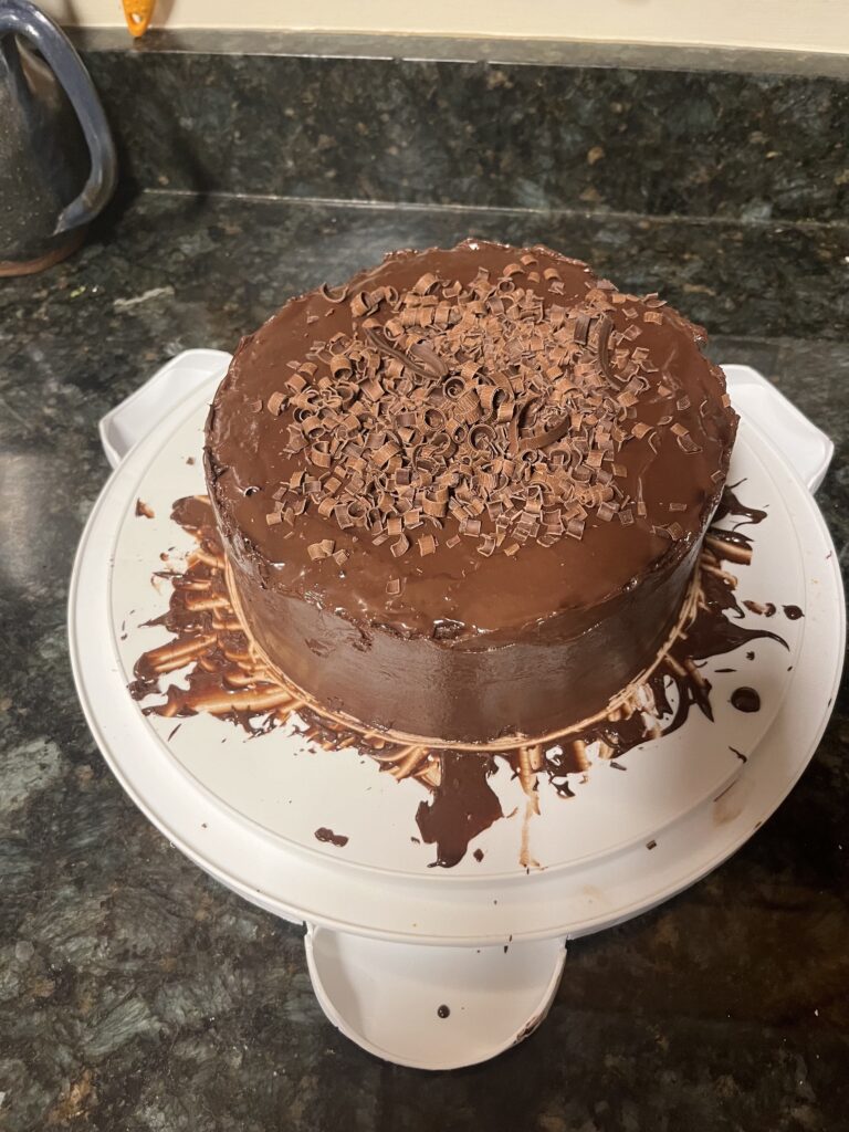 Chocolate cake sitting on a white cake holder base.