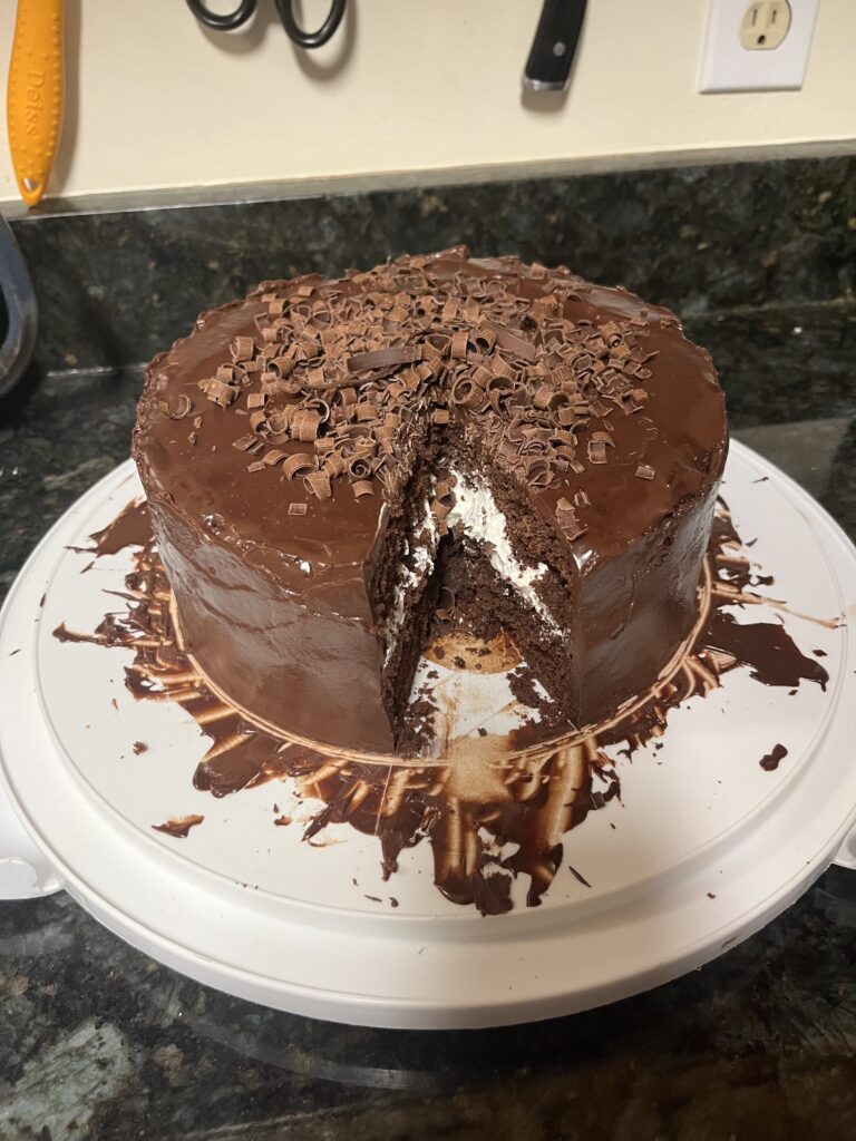 Chocolate cake, with a slice missing. White cream filing showing between the layers.