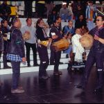 A group of men with drums in an indoor space doing a show.