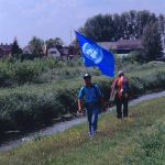 Young Indian man carrying a UN flag in his backpack as he walks.