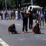 Three young teenagers chalking in the street in front of Nato.